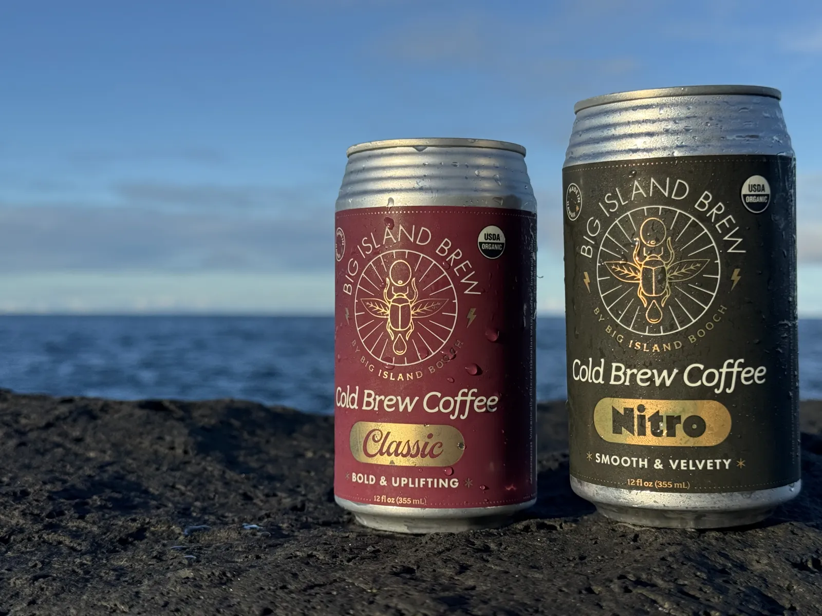 Big Island Brew Cold Brew Coffee Classic and Nitro cans with condensation on lava rock at golden hour