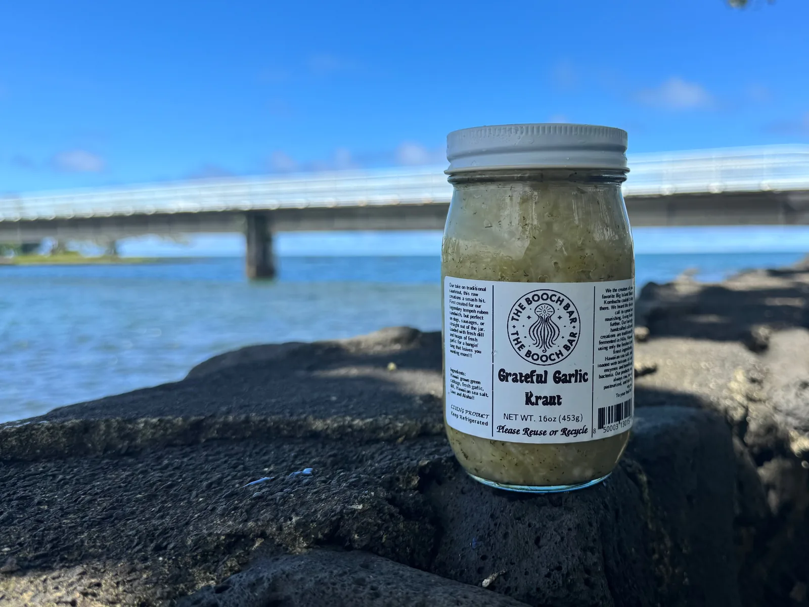 A 16 oz jar of Big Island Booch Grateful Garlic kraut on lava rock at Hilo Bay